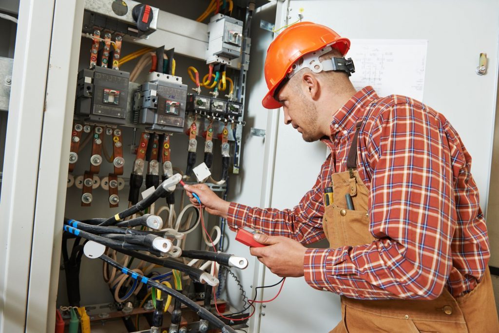 Monteur meet een verdeelinrichting door met een multimeter