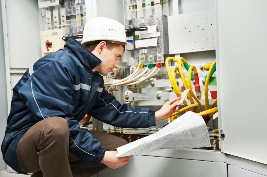 Technicus controleert een schakelkast aan de hand van een installatietekening